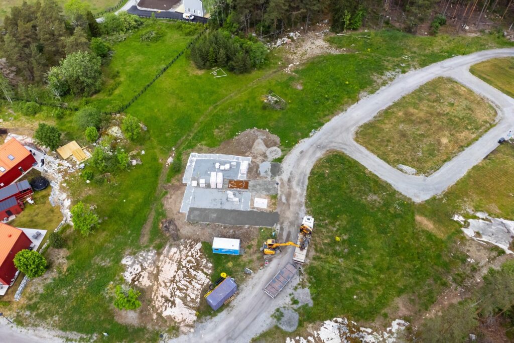 Flygfoto över en obebyggd tomt där grundläggningen påbörjats, vilket illustrerar hur detaljplanen och tomtgränser sätter ramarna för husets placering.